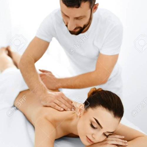 Spa Woman. Beauty Treatment. Beautiful Young Healthy Caucasian girl relaxing with hand Massage Procedure In The Spa Salon. Masseur Massaging her Back. Body Care. Skin Care, Wellness, Wellbeing.